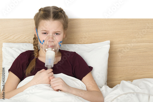 girl with inhaler mask - respiratory problems for asthma. girl with a mask inhaler lies with a toy in bed and breathes adrenaline. health care and sick child concept