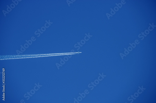 Plane flys very high in the blue coudless sky