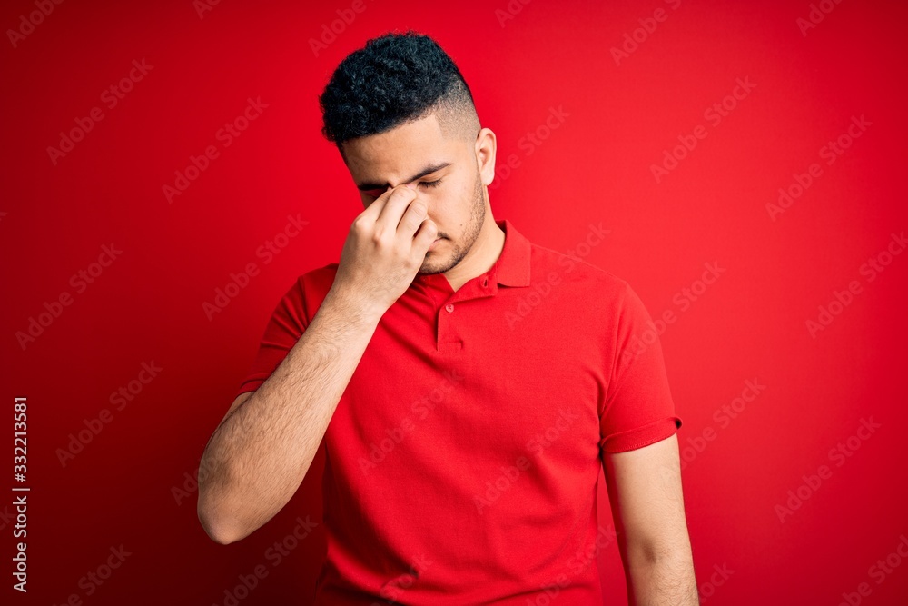 Young handsome man wearing red casual polo standing over isolated background tired rubbing nose and eyes feeling fatigue and headache. Stress and frustration concept. Young handsome man wearing red casual polo standing over isolated background tired rubbing nose and eyes feeling fatigue and headache. Stress and frustration concept.