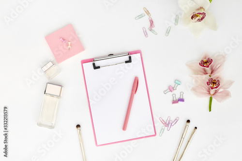 Mockup with clipboard, orchid flowers and clips. feminine office table. Flat lay, top view.