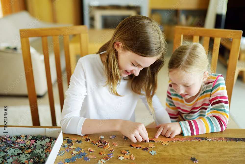 Cute young girls playing puzzles at home. Children connecting jigsaw puzzle  pieces in a living room table. Kids assembling a jigsaw puzzle. Fun family  leisure. Photos | Adobe Stock