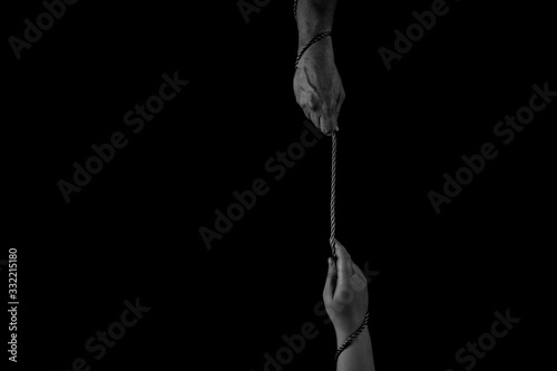 Helping Hand, Hand reaching, trying to pull up with rope and rescue, black background, copy space