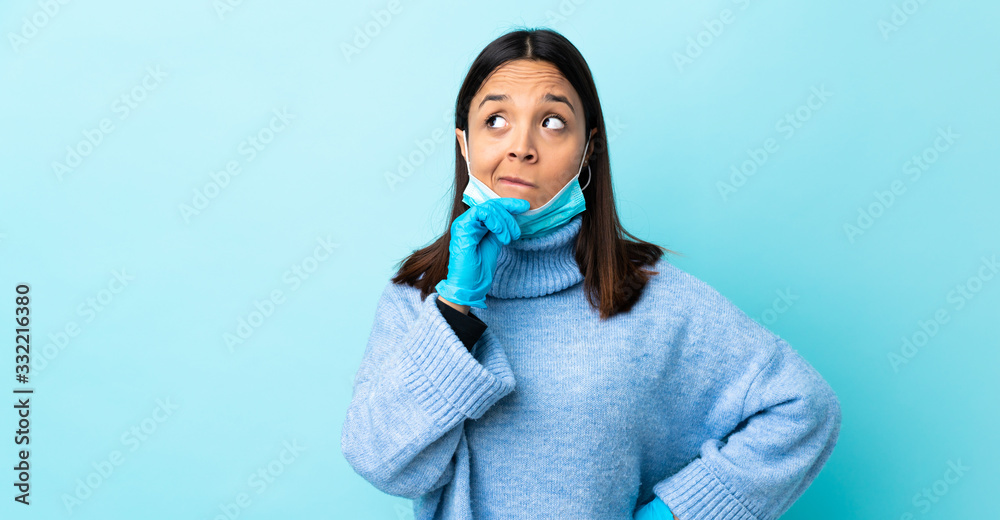 Young brunette mixed race woman protecting from the coronavirus with a mask and gloves over isolated blue background having doubts and thinking Young brunette mixed race woman protecting from the coronavirus with a mask and gloves over isolated blue background having doubts and thinking