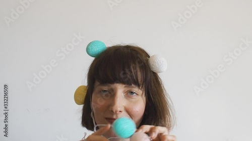 Cute happy girl easter portrait with egg shaped decor lights on her head. Spring pastel colors. Young woman smiling and fooling around.
