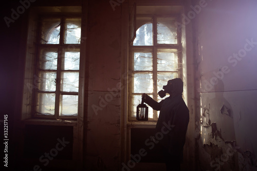 Dramatic portrait of a woman wearing a gas mask in a ruined building.