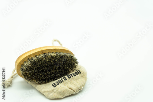 Beard brush with natural bristles, on its case located on the left of the image with white background with space on the right. Concept facial care for men