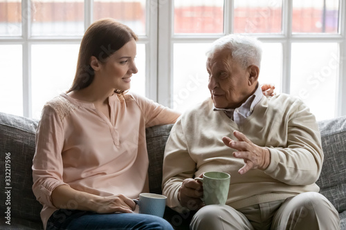 Cuadro en lienzo Talk during teatime with aged man, caregiver listens life memories stories of old 75s patient seated on sofa in cozy living room