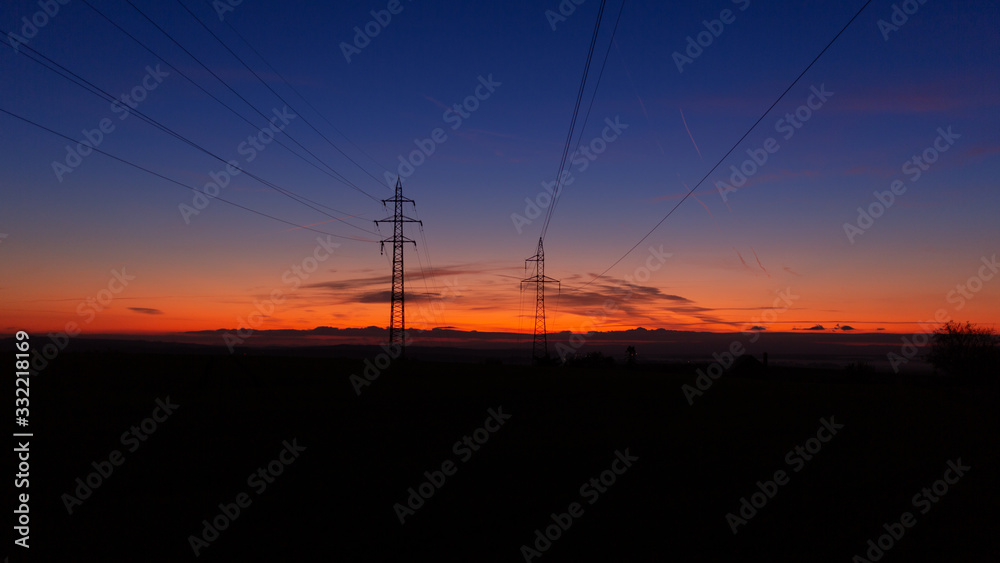 High voltage poles standing on the background of the blue hour