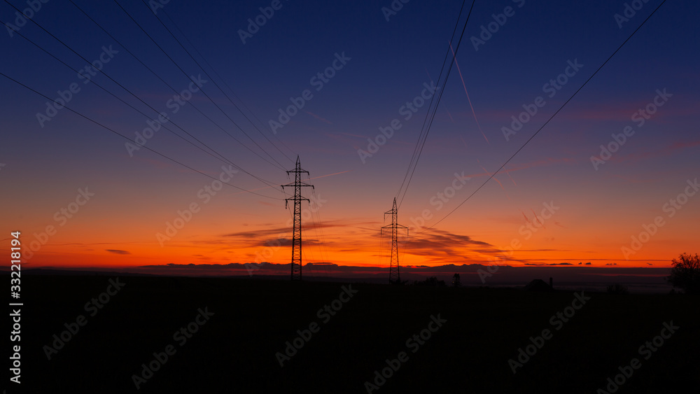 High voltage poles standing on the background of the blue hour