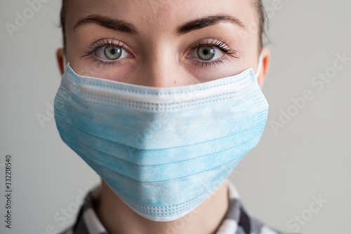 Girl with medical mask to protect her from virus. Coronavirus pandemic. Woman with mask standing . People being hospitalized, diagnosed, often put in carantine (isolation) to stop spreading Corona. photo