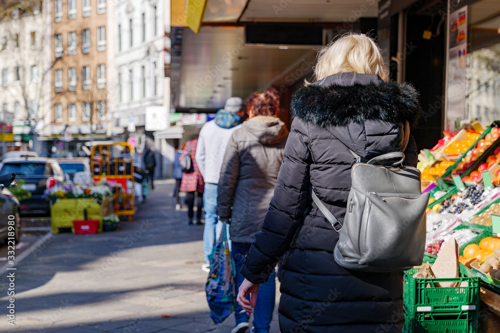 Selected focus, European people queue outside in front of food stall and supermarket during quarantine for COVID-19 virus in Düsseldorf, Germany.