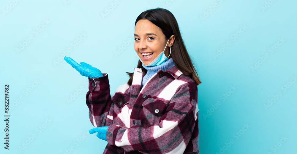 Young brunette mixed race woman protecting from the coronavirus with a mask and gloves over isolated blue background extending hands to the side for inviting to come Young brunette mixed race woman protecting from the coronavirus with a mask and gloves over isolated blue background extending hands to the side for inviting to come