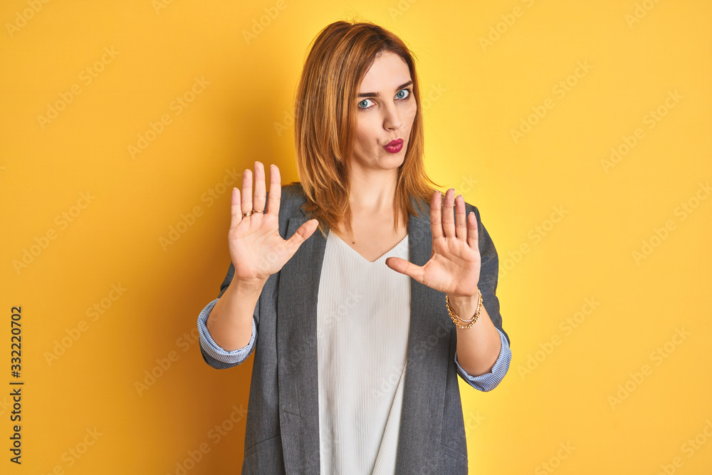 Redhead caucasian business woman over yellow isolated background disgusted expression, displeased and fearful doing disgust face because aversion reaction. With hands raised. Annoying concept. Redhead caucasian business woman over yellow isolated background disgusted expression, displeased and fearful doing disgust face because aversion reaction. With hands raised. Annoying concept.