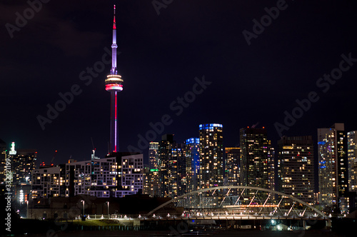 Night view on Downtown Toronto skyscrapers with brightly lit windows with the colorfully lit CN Tower, Toronto, Ontario, Canada © Vadim Rodnev