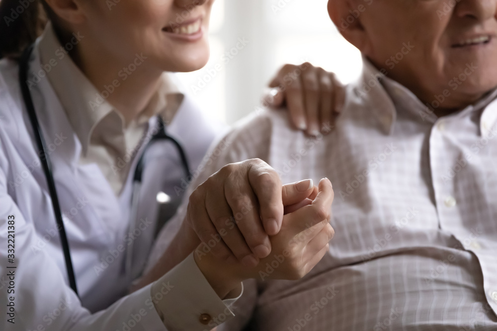 Close up image smiling friendly positive nurse in white coat stethoscope on neck hold hand hugs of old man patient. Social worker, eldercare, geriatric medicine, medical insurance, health care concept Close up image smiling friendly positive nurse in white coat stethoscope on neck hold hand hugs of old man patient. Social worker, eldercare, geriatric medicine, medical insurance, health care concept