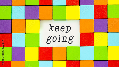 Keep Going typed on white paper surrounded by colourful blocks in a conceptual image of inspiration and motivation.