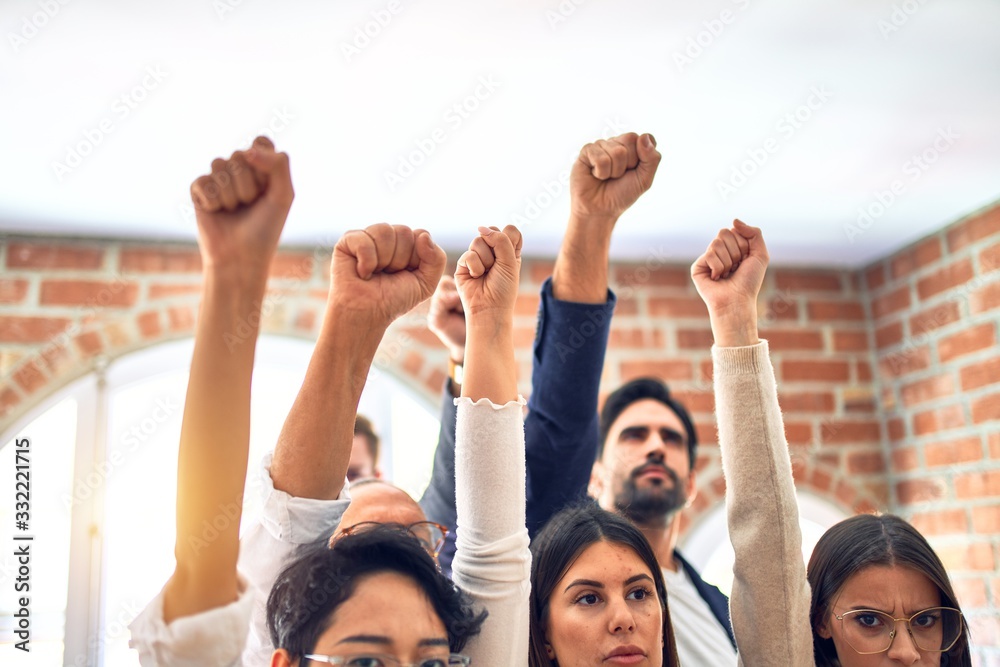 Group of business workers standing with fists up at the office Group of business workers standing with fists up at the office