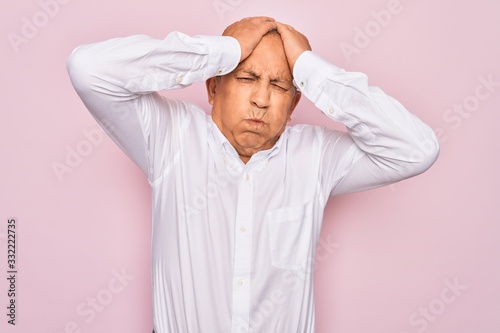 Senior handsome grey-haired man wearing elegant shirt over isolated pink background suffering from headache desperate and stressed because pain and migraine. Hands on head.