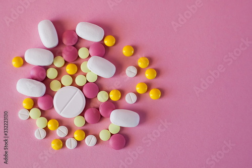 Assorted pharmaceutical medicine! Pills of different colors and shapes on a pink background. Top view. The concept of the treatment of diseases! Coronavirus and antibiotics!