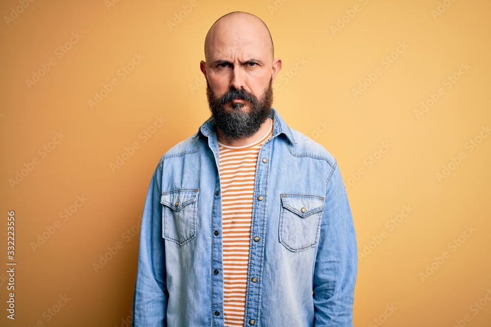 Handsome bald man with beard wearing casual denim jacket and striped t-shirt skeptic and nervous, frowning upset because of problem. Negative person. Handsome bald man with beard wearing casual denim jacket and striped t-shirt skeptic and nervous, frowning upset because of problem. Negative person.