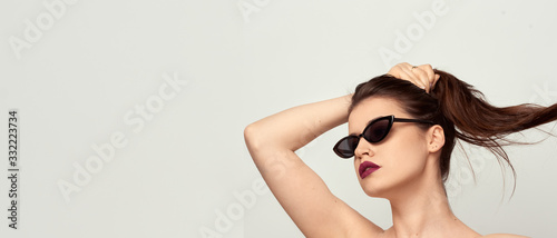 beautiful young girl with brown hair in fashionable glasses posing on a white background with bare shoulders, empty space for text