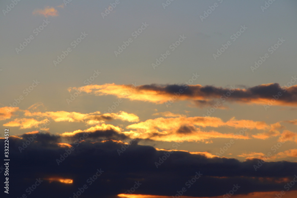 Clouds in the blue sky at sunset or dawn backlit by the sun. Place for text and design