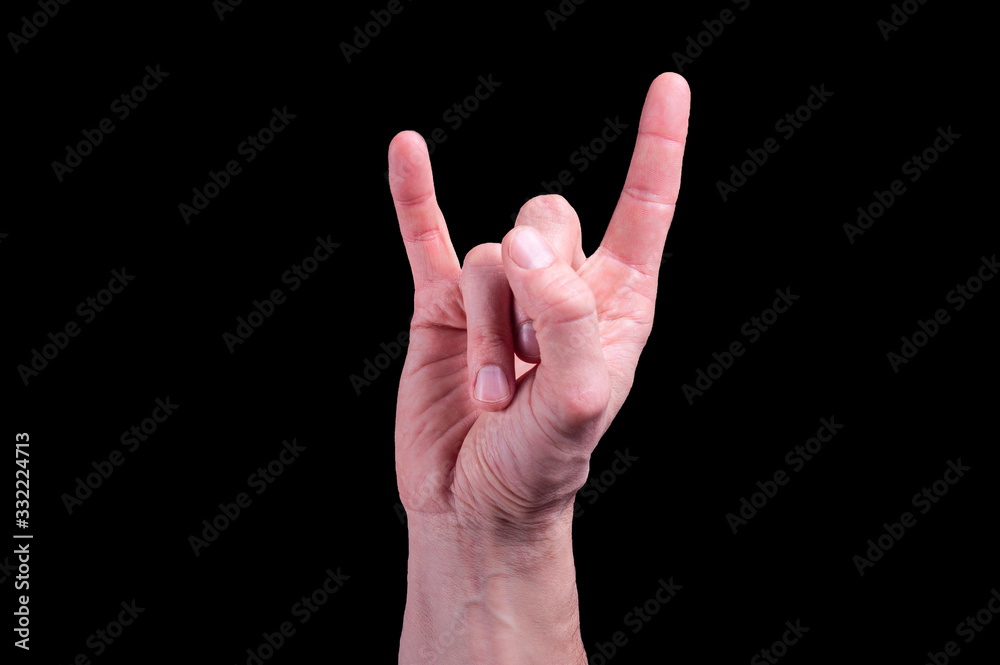 Hand of euroopean human shows the sign of the horns on isolated black background