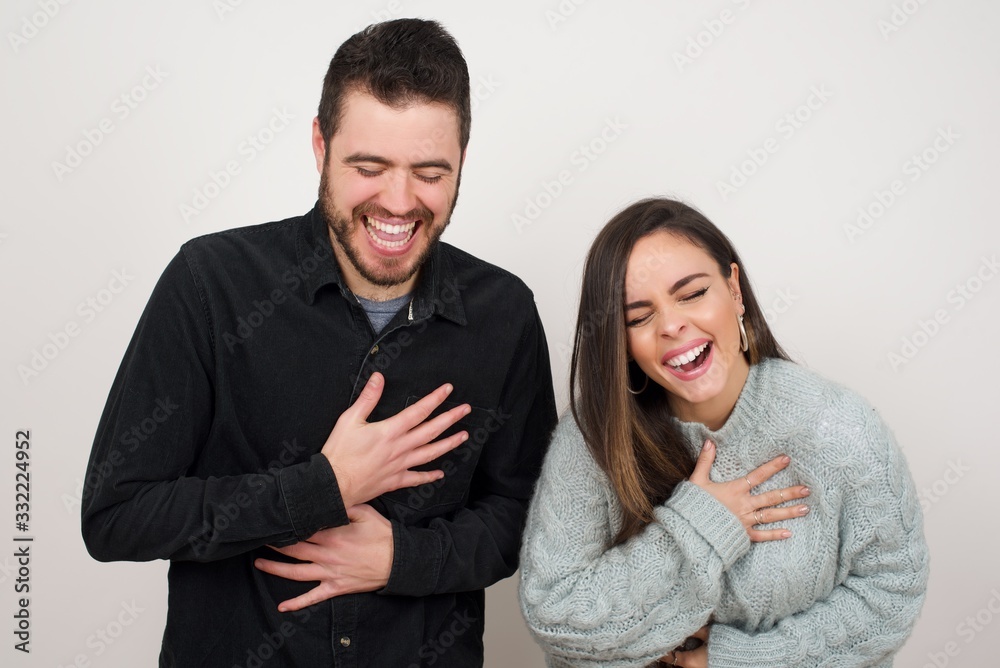 Joyful European student keeps hands crossed, laughs at good joke, wears casual clothes and round spectacles, standing indoors. Happy young woman with long hair poses against gray wall. Joyful European student keeps hands crossed, laughs at good joke, wears casual clothes and round spectacles, standing indoors. Happy young woman with long hair poses against gray wall.