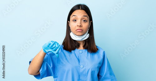 Surgeon woman over isolated blue background showing thumb down with negative expression
