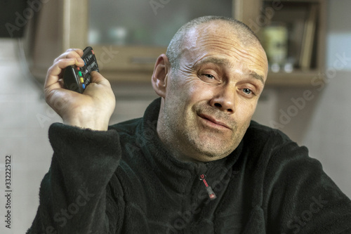 Slika na platnu A man with a skeptical smile watches fake news on television