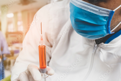 Medical vaccine syringe for medicine injection treatment holding in a hand of the doctor Doctor wearing medical mask for prevent germs Coronavirus Covid-19.