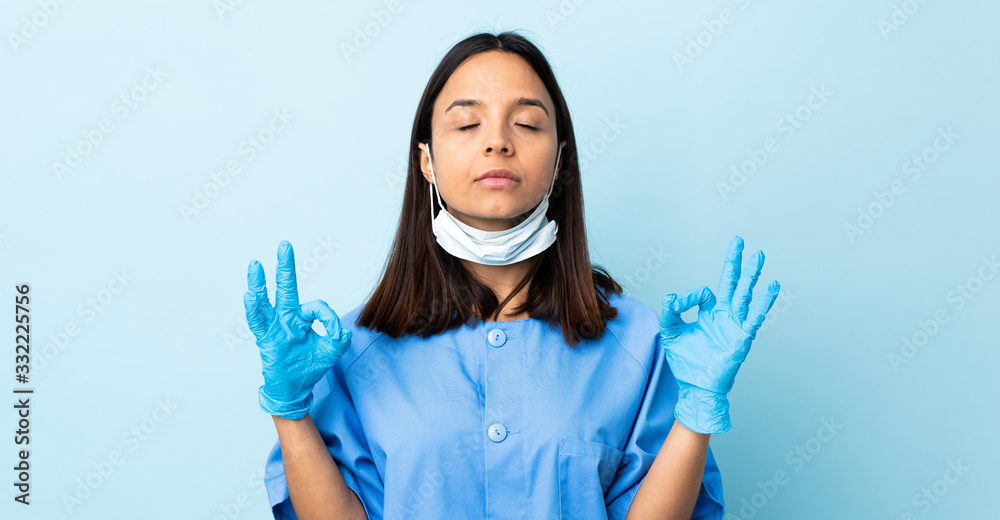 Surgeon woman over isolated blue background in zen pose