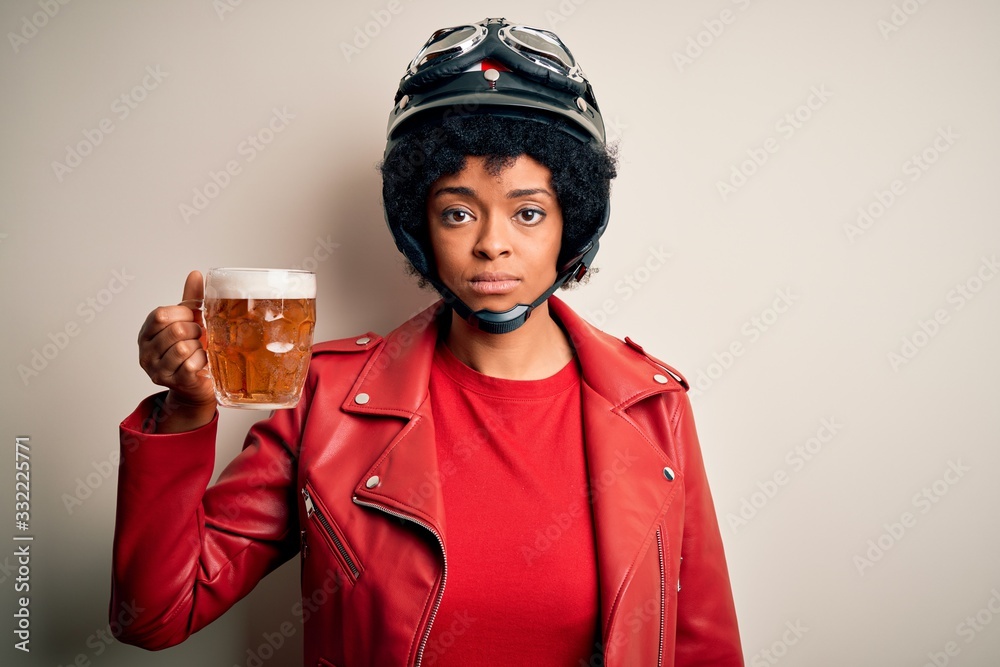 Young African American afro motorcyclist woman with curly hair drinking jar of beer with a confident expression on smart face thinking serious Young African American afro motorcyclist woman with curly hair drinking jar of beer with a confident expression on smart face thinking serious