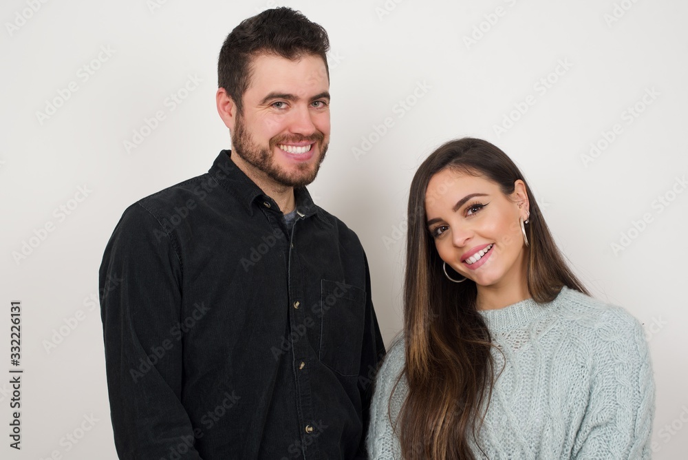 Shy girl smiling looking to the camera. Caucasian charming girl sanding against gray studio background feeling shy. Shy girl smiling looking to the camera. Caucasian charming girl sanding against gray studio background feeling shy.
