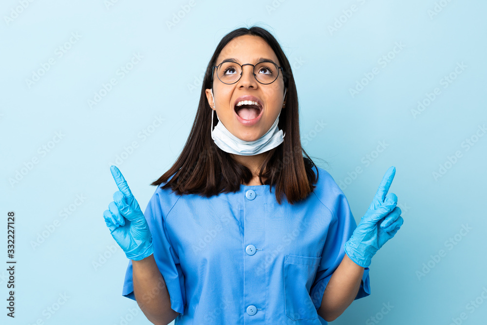 Surgeon woman over isolated blue background surprised and pointing up Surgeon woman over isolated blue background surprised and pointing up