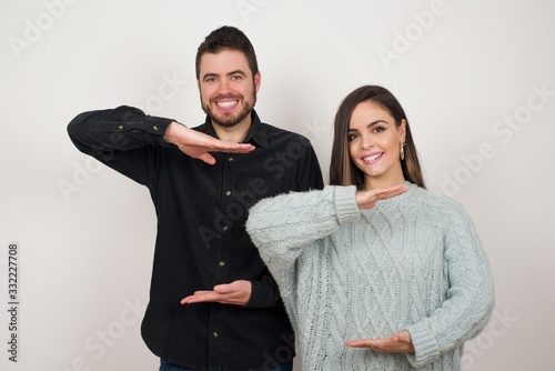 Young beautiful woman over isolated background gesturing with hands showing big and large size sign, measure symbol. Smiling looking at the camera. Measuring concept.