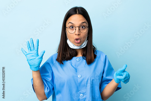 Surgeon woman over isolated blue background counting six with fingers