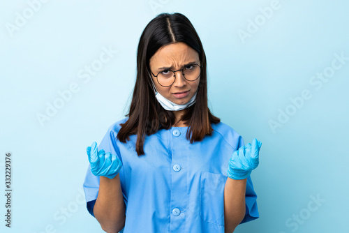 Surgeon woman over isolated blue background making money gesture but is ruined