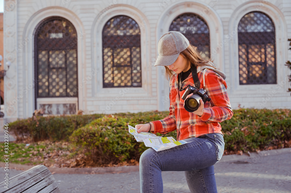 Obraz premium Girl with a map and a camera. Woman traveling and taking pictures outdoors. Photographer Traveling Attractions Walk Hobby Vacation Concept. Nice day in Europe.