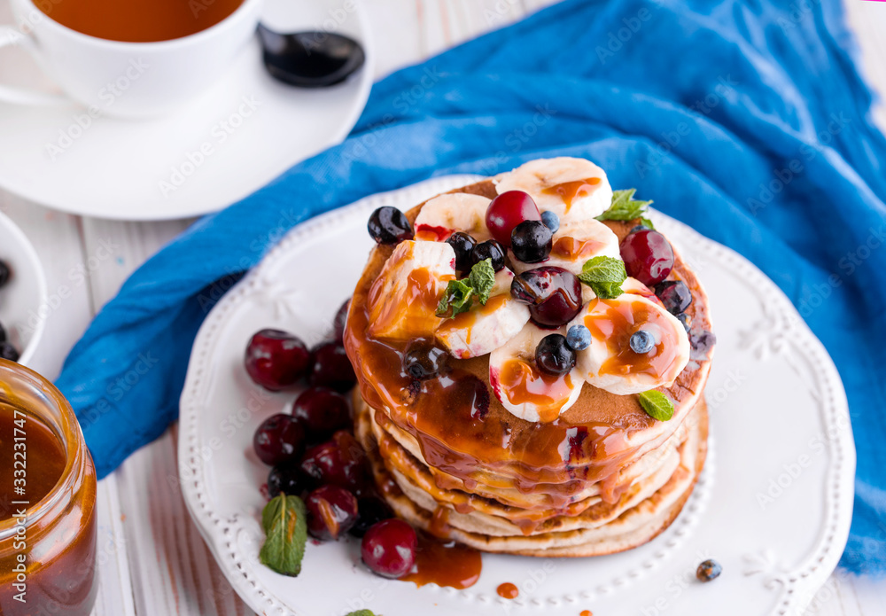 Delicious pancakes with banana, berries, mint and salted caramel in a plate. Delicious pancakes with banana, berries, mint and salted caramel in a plate.