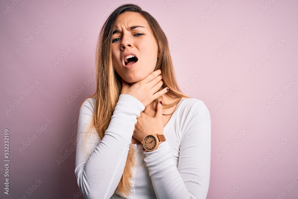 Young beautiful blonde woman with blue eyes wearing white t-shirt over pink background shouting suffocate because painful strangle. Health problem. Asphyxiate and suicide concept. Young beautiful blonde woman with blue eyes wearing white t-shirt over pink background shouting suffocate because painful strangle. Health problem. Asphyxiate and suicide concept.
