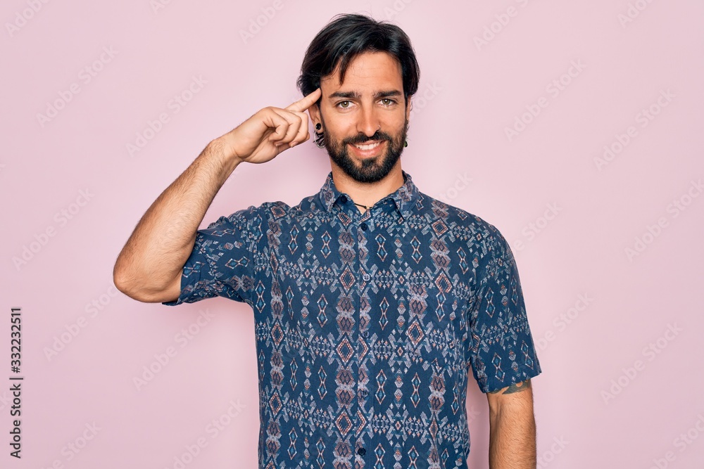 Young handsome hispanic bohemian man wearing hippie style over pink background Smiling pointing to head with one finger, great idea or thought, good memory Young handsome hispanic bohemian man wearing hippie style over pink background Smiling pointing to head with one finger, great idea or thought, good memory