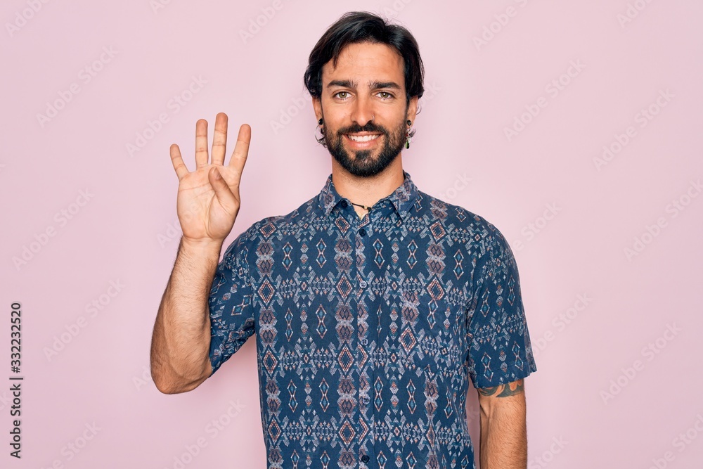 Fototapeta premium Young handsome hispanic bohemian man wearing hippie style over pink background showing and pointing up with fingers number four while smiling confident and happy.