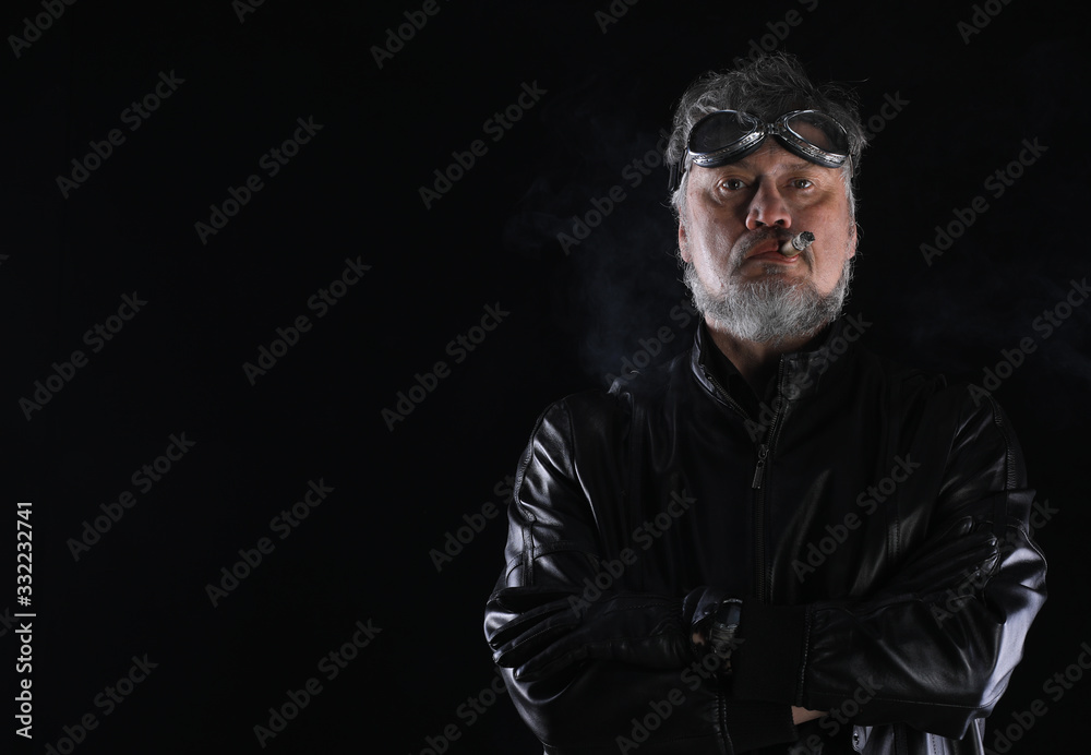studio portrait of an old biker with a cigar on a black background studio portrait of an old biker with a cigar on a black background