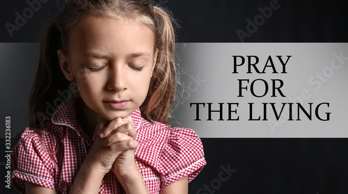 Praying little girl on dark...