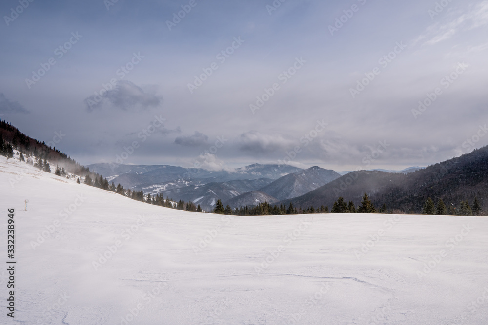 Snow covered meadow in the mountains with mountains in the background and a beautiful arch, Slovakia Mala Fatra