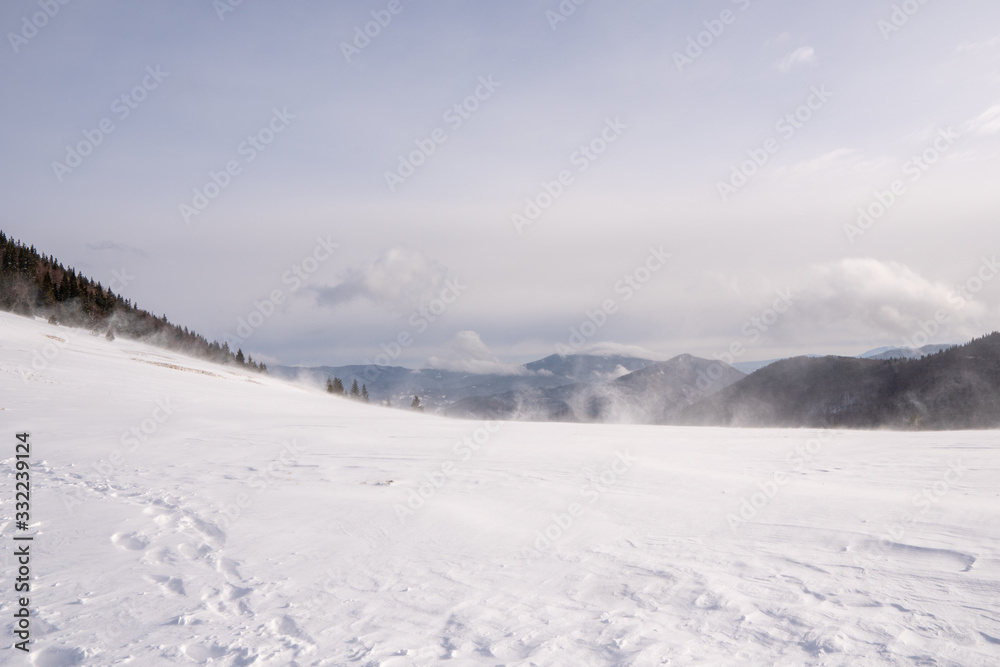 Snow covered meadow in the mountains with mountains in the background and a beautiful arch, Slovakia Mala Fatra