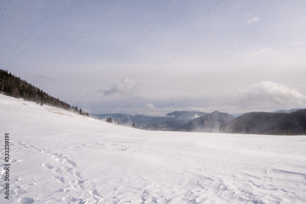 Snow covered meadow in the mountains with mountains in the background and a beautiful arch, Slovakia Mala Fatra