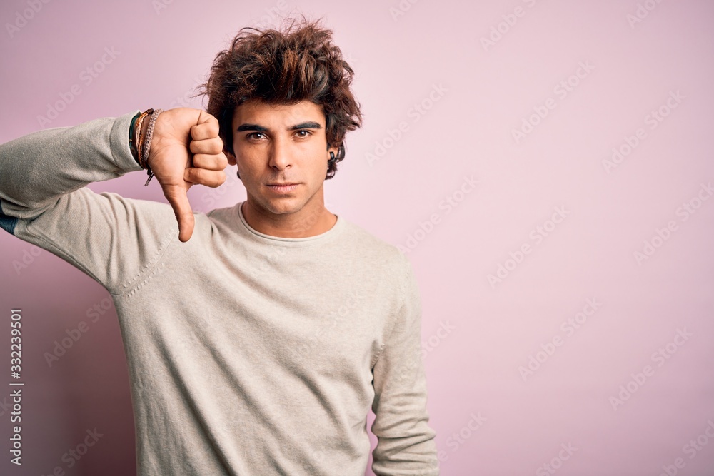 Young handsome man wearing casual t-shirt standing over isolated pink background looking unhappy and angry showing rejection and negative with thumbs down gesture. Bad expression. Young handsome man wearing casual t-shirt standing over isolated pink background looking unhappy and angry showing rejection and negative with thumbs down gesture. Bad expression.