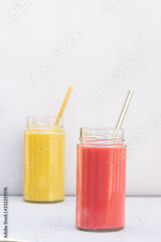 Yellow Banana, pear and red apple, raspberry smoothie. Glass, jar, metal straw. Health, vegetarian, vegan breakfast, drink. No plastic, Ecology. Grey background, copy space. Vertical. 